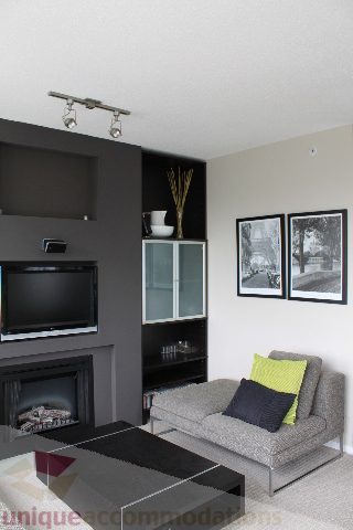 Furnished living room with gray sofa, black coffee table, and wall-mounted TV. - 2103 - 1001 Homer Street, Vancouver Downtown