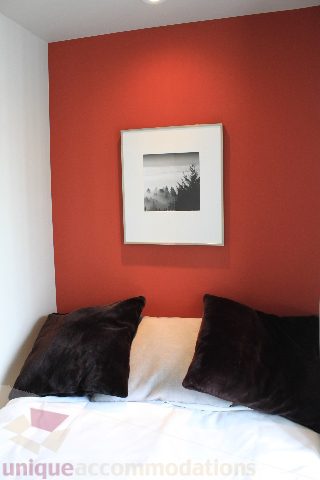 Furnished bedroom with red accent wall and black and white artwork. - 2103 - 1001 Homer Street, Vancouver Downtown