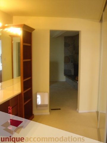 Bright kitchen with wooden cabinets and countertop, leading to a hallway with a door. - 100 Lions Bay Avenue, West Vancouver