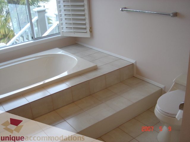 Bright bathroom with steps leading to a bathtub, natural light from a window. - 100 Lions Bay Avenue, West Vancouver