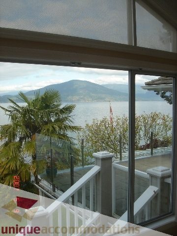 Bright living room with stunning ocean view and palm trees. - 100 Lions Bay Avenue, West Vancouver