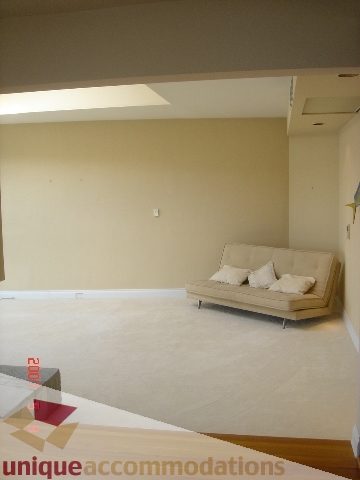 Spacious living room with beige couch and white rug, modern design. - 100 Lions Bay Avenue, West Vancouver
