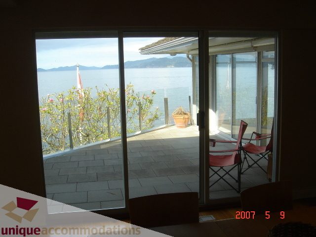 Bright living room with large glass doors opening to a stunning ocean view. - 100 Lions Bay Avenue, West Vancouver