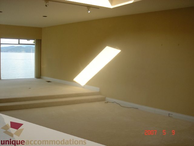 Bright living room with large windows, city view, and sunlight streaming in. - 100 Lions Bay Avenue, West Vancouver