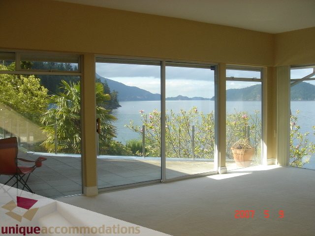 Bright living room with floor-to-ceiling glass doors, offering stunning views of the bay and mountains. - 100 Lions Bay Avenue, West Vancouver