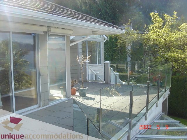 Bright sunlit patio with glass railings, overlooking lush greenery and a serene outdoor setting. - 100 Lions Bay Avenue, West Vancouver