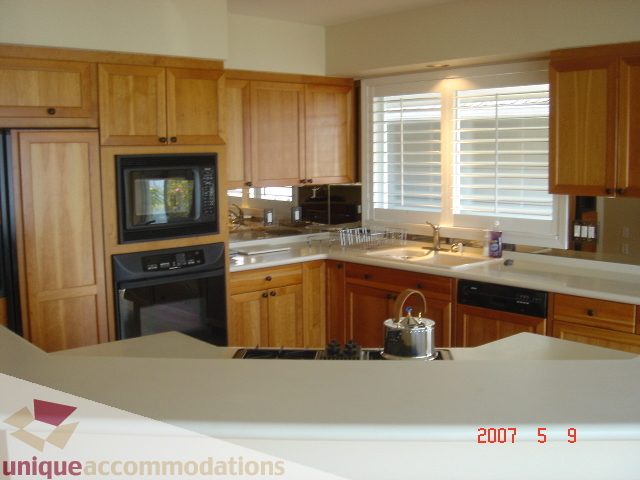 Bright kitchen with light wood cabinets, granite countertops, and a window with blinds. - 100 Lions Bay Avenue, West Vancouver