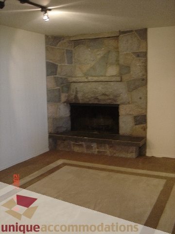 Living room with stone fireplace and carpeted floor. - 100 Lions Bay Avenue, West Vancouver