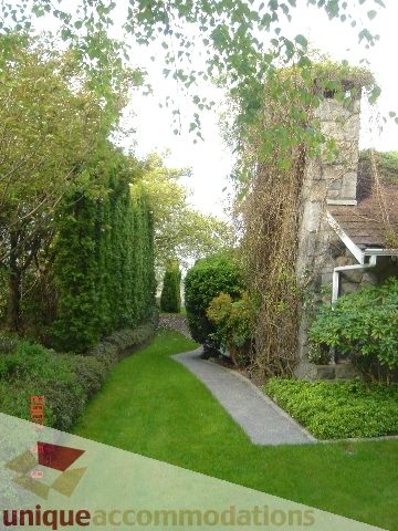 Furnished garden with stone archway and lush greenery. - 100 Lions Bay Avenue, West Vancouver