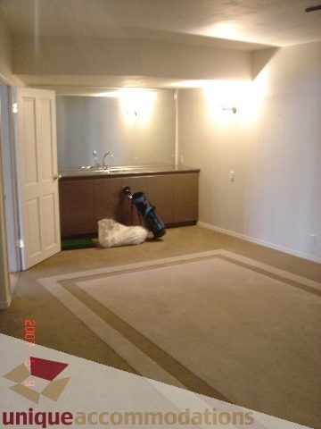 Furnished living room with carpeted floors and a kitchen counter in the background. - 100 Lions Bay Avenue, West Vancouver