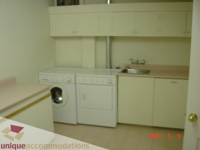 Bright kitchen with white appliances, light countertops, and tiled floor. - 100 Lions Bay Avenue, West Vancouver