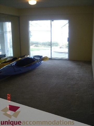 Living room with large windows, carpeted floor, and kayak storage. - 100 Lions Bay Avenue, West Vancouver