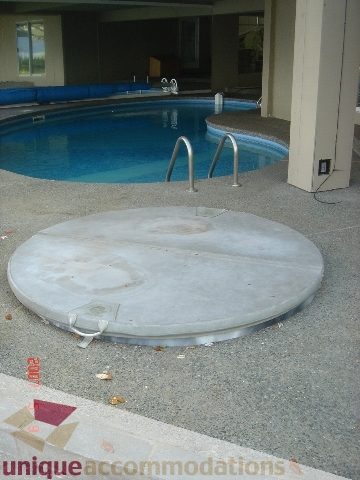 Outdoor patio with a circular concrete table and a swimming pool in the background. - 100 Lions Bay Avenue, West Vancouver