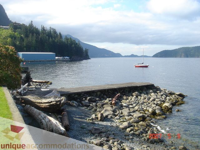 Furnished living room with ocean view and rocky shoreline. - 100 Lions Bay Avenue, West Vancouver