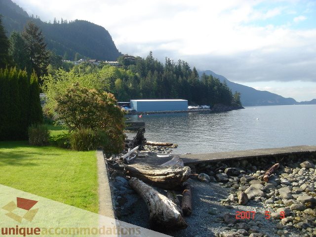 Bright living room with a view of the mountains and a pebble beach nearby. - 100 Lions Bay Avenue, West Vancouver