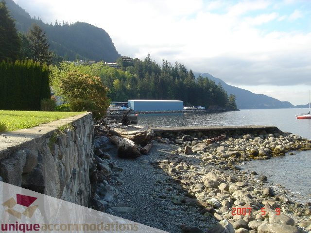 Furnished living room with stone walls and a view of the water. - 100 Lions Bay Avenue, West Vancouver