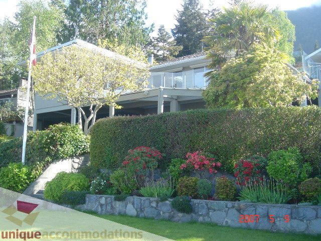 Furnished 4-bedroom house with lush greenery and stone wall. - 100 Lions Bay Avenue, West Vancouver