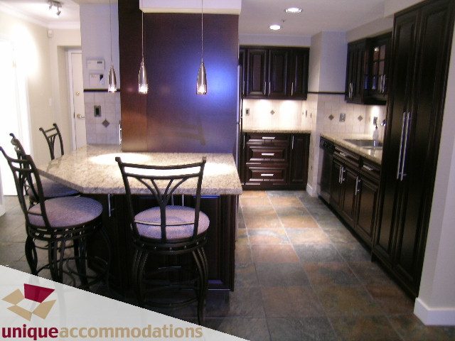 Bright kitchen with dark wood cabinets, granite countertops, and pendant lights. - 2C - 199 Drake Street, Vancouver Downtown