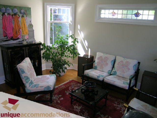 Furnished living room with floral-patterned chairs and a glass coffee table, natural light from windows. - 4177 West 15th Avenue, Vancouver West Side