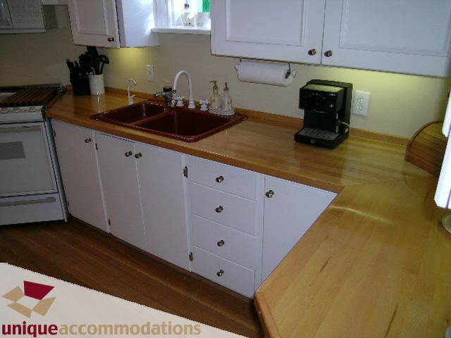 Bright kitchen with white cabinets, wooden countertops, and a red sink. - 4177 West 15th Avenue, Vancouver West Side