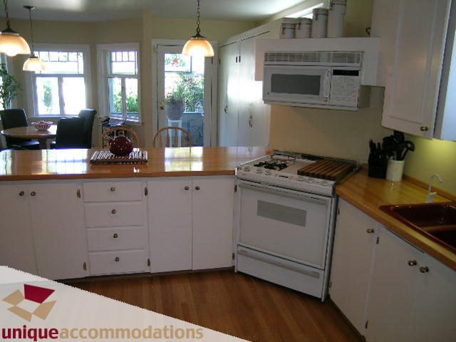 Bright kitchen with white cabinetry, wooden countertops, and hardwood floors. - 4177 West 15th Avenue, Vancouver West Side