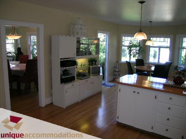 Bright kitchen with white cabinetry, hardwood floors, and a view of greenery outside. - 4177 West 15th Avenue, Vancouver West Side