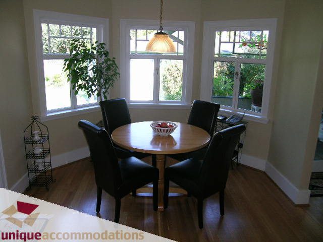 Bright dining area with hardwood floors, large windows, and a round table with black chairs. - 4177 West 15th Avenue, Vancouver West Side