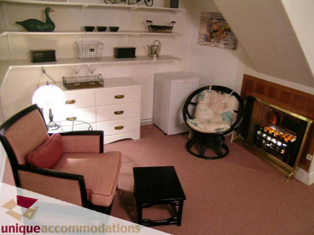 Furnished living room with a cozy armchair, small table, and a fireplace. - 4177 West 15th Avenue, Vancouver West Side