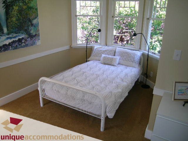 Bright bedroom with white furniture, large windows, and a cozy ambiance. - 4177 West 15th Avenue, Vancouver West Side
