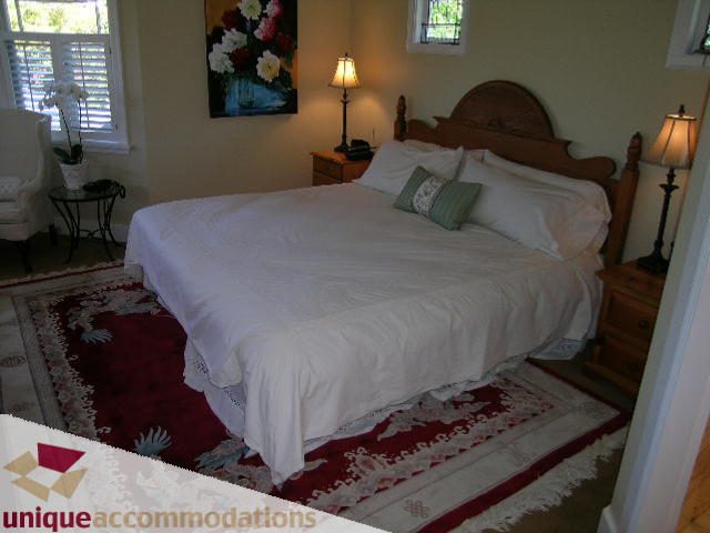 Spacious bedroom with large bed, wooden headboard, and floral rug. - 4177 West 15th Avenue, Vancouver West Side