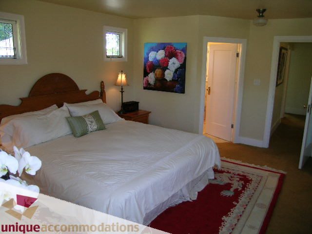 Spacious bedroom with two twin beds, white linens, and a red rug. - 4177 West 15th Avenue, Vancouver West Side