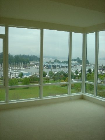 Bright living room with expansive city view and marina, featuring large windows and carpeted floor. - 902 - 1925 Alberni Street, Vancouver Downtown