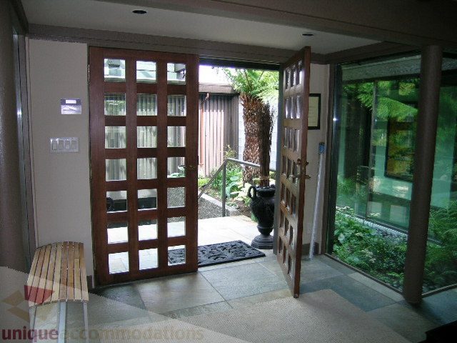 Framed glass doors lead to a lush garden, showcasing natural light and greenery. - 455 Keith Road, West Vancouver