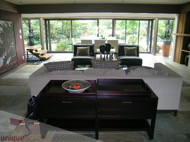 Spacious living room with large windows, modern furniture, and a view of greenery outside. - 455 Keith Road, West Vancouver