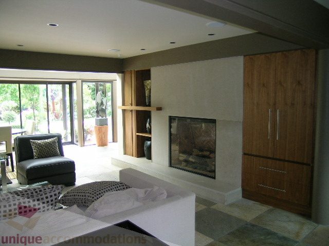 Furnished living room with modern fireplace, hardwood cabinets, and large windows. - 455 Keith Road, West Vancouver