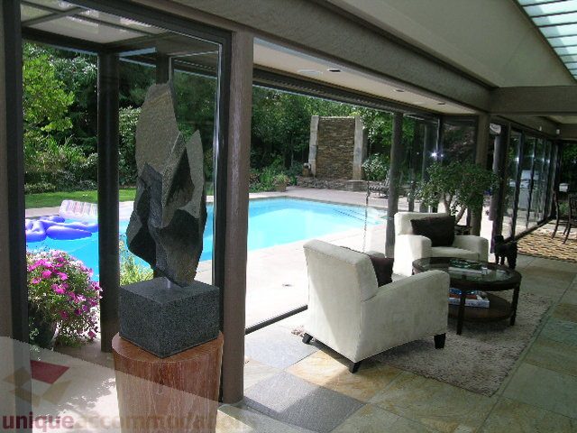 Furnished living room with large windows, pool view, and modern decor. - 455 Keith Road, West Vancouver