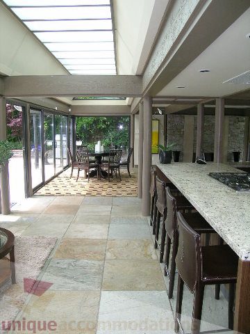 Furnished dining area with granite countertops and large windows, offering a view of the garden. - 455 Keith Road, West Vancouver
