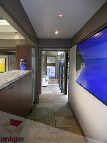 Modern kitchen with granite countertops and hardwood floors, leading to a spacious living area with a large screen. - 455 Keith Road, West Vancouver