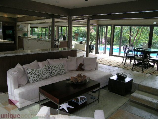 Spacious living room with large windows, modern furniture, and a view of the pool area. - 455 Keith Road, West Vancouver