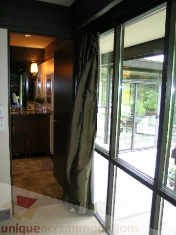 Bright living room with large windows and hardwood floors, leading to a patio. - 455 Keith Road, West Vancouver
