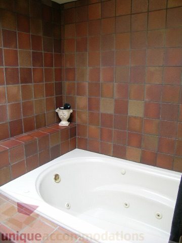 Bathroom with terracotta tile walls and a white tub. - 455 Keith Road, West Vancouver
