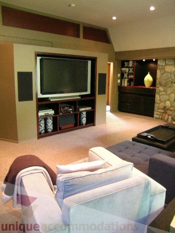 Living room with modern furniture, large TV, and stone accent wall. - 455 Keith Road, West Vancouver