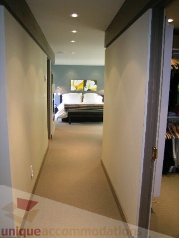 Furnished hallway leading to a cozy bedroom with a large window and artwork. - 455 Keith Road, West Vancouver