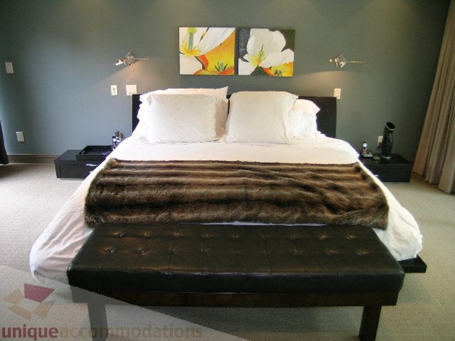 Master bedroom with modern decor, fur throw, and wall art. - 455 Keith Road, West Vancouver