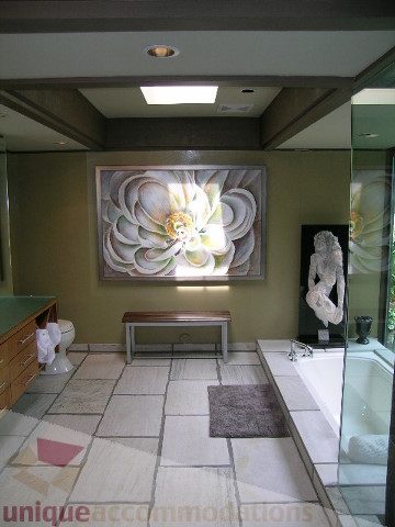Furnished bathroom with green walls, large floral artwork, and modern sink. - 455 Keith Road, West Vancouver