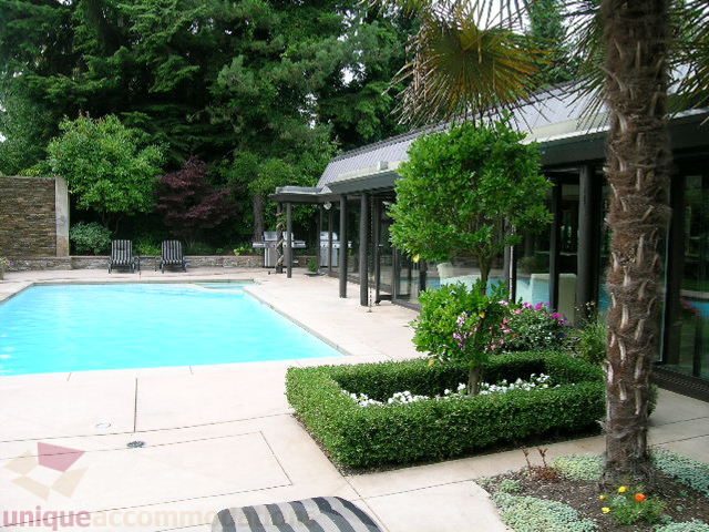 Spacious patio with pool, lush greenery, and modern house in the background. - 455 Keith Road, West Vancouver