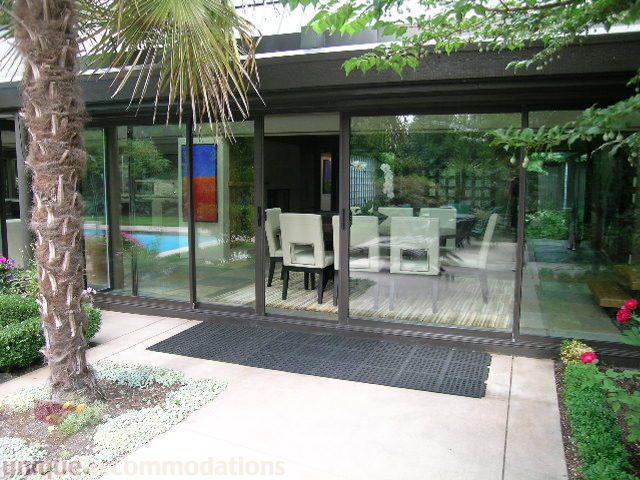 Furnished patio with glass walls, outdoor dining set, and palm tree. - 455 Keith Road, West Vancouver