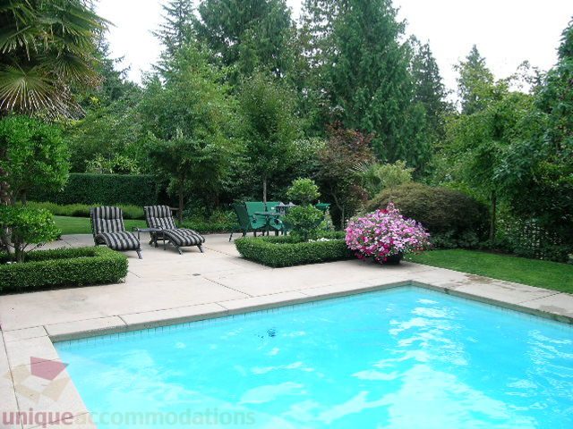 Furnished patio with lounge chairs, lush greenery, and a sparkling pool. - 455 Keith Road, West Vancouver
