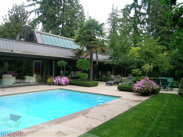 Furnished living room with large windows and greenery outside. - 455 Keith Road, West Vancouver