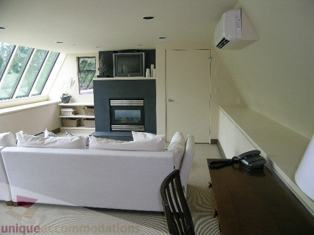 Bright living room with white furniture, large windows, and a modern fireplace. - 455 Keith Road, West Vancouver